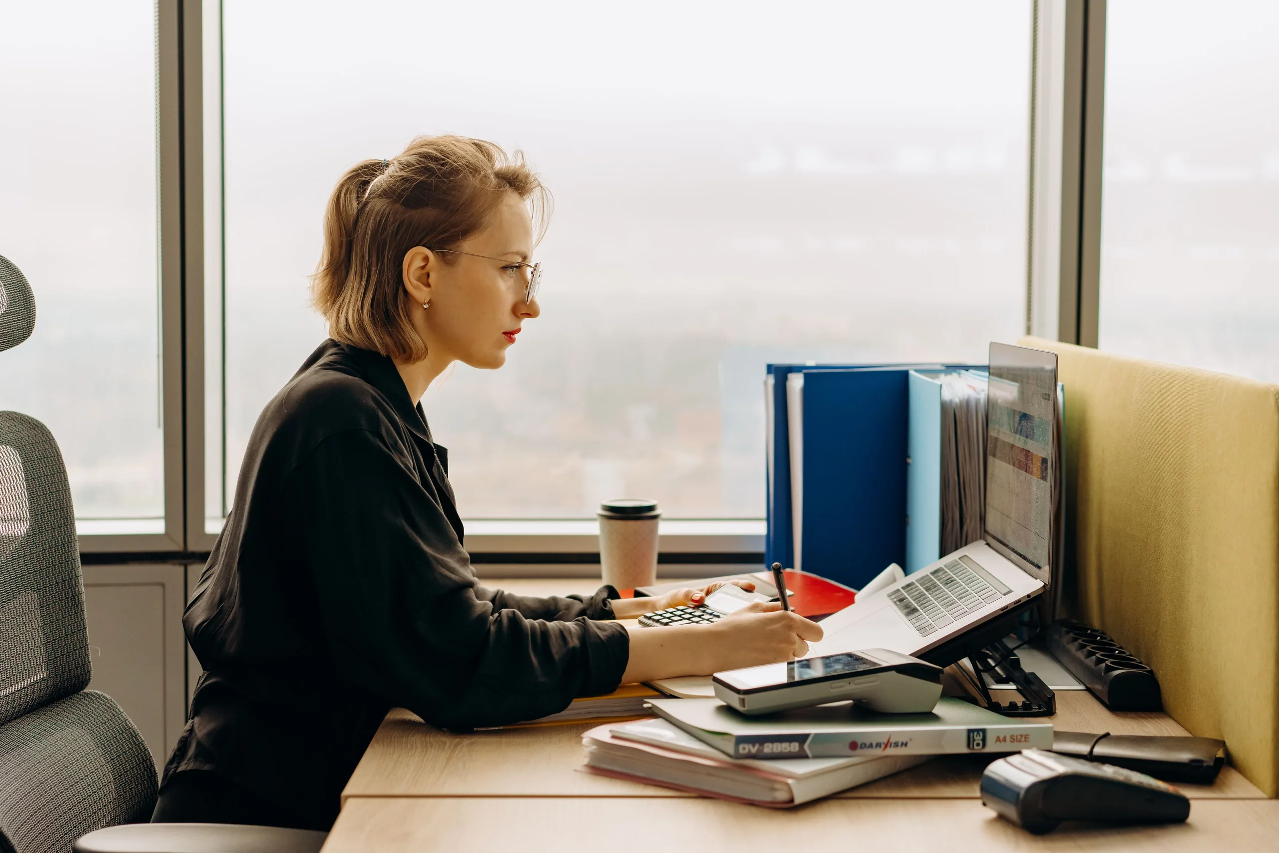 An accountant working through a tax return at a desk with a laptop and calculator