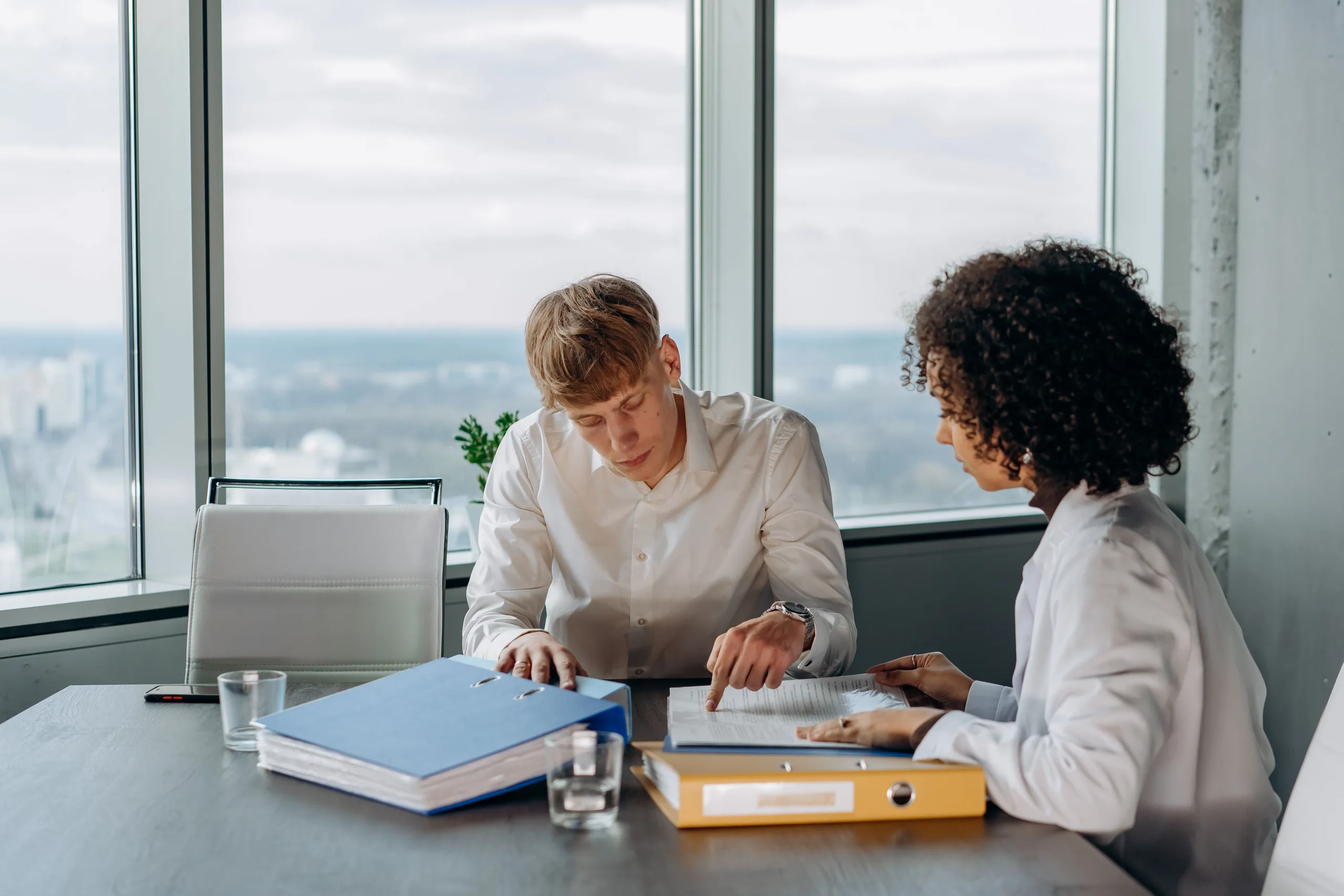 A partner and a practice manager at a Canadian accounting firm working through the week’s jobs together beside an office window