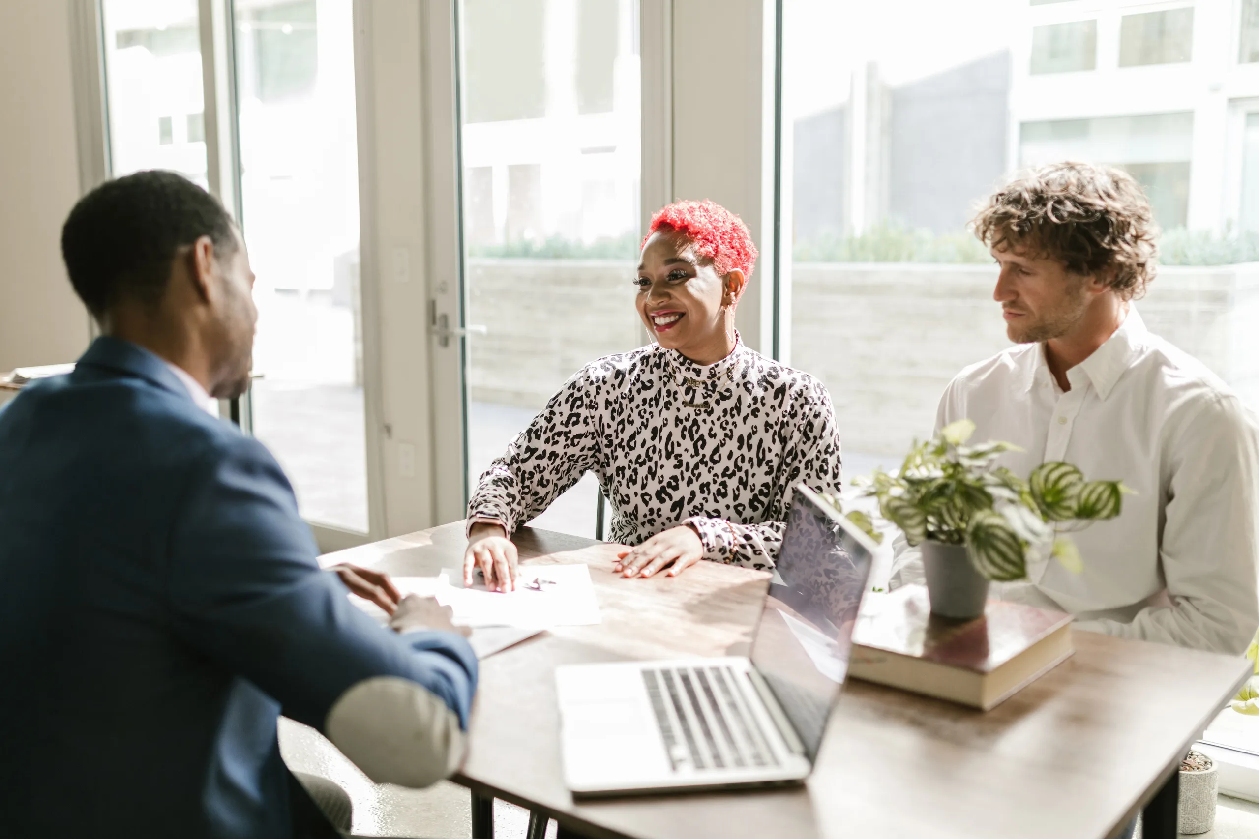 Three accountants reviewing a client file together at a sunlit office table