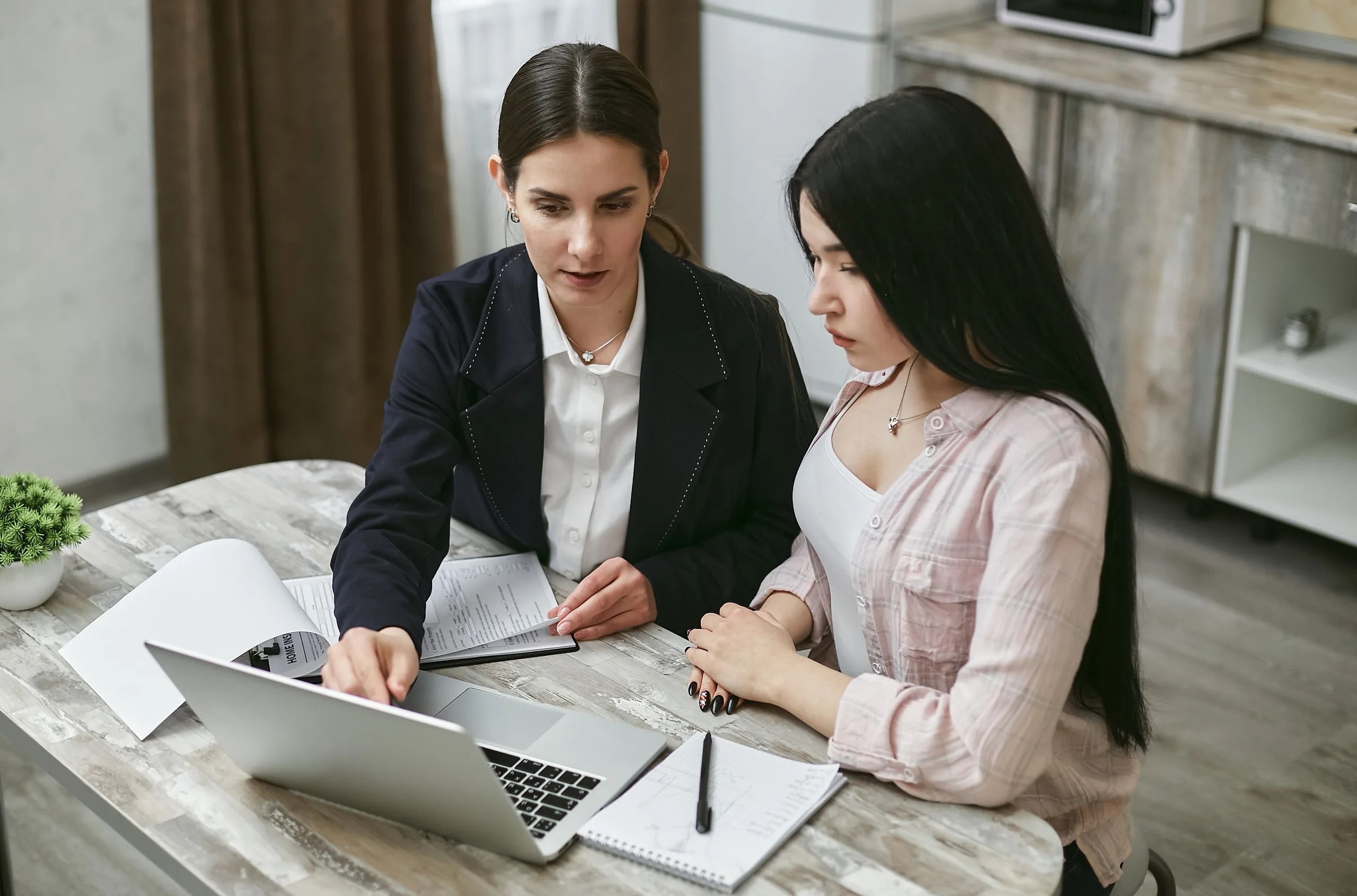Two colleagues reviewing settings together on a laptop in a bright office