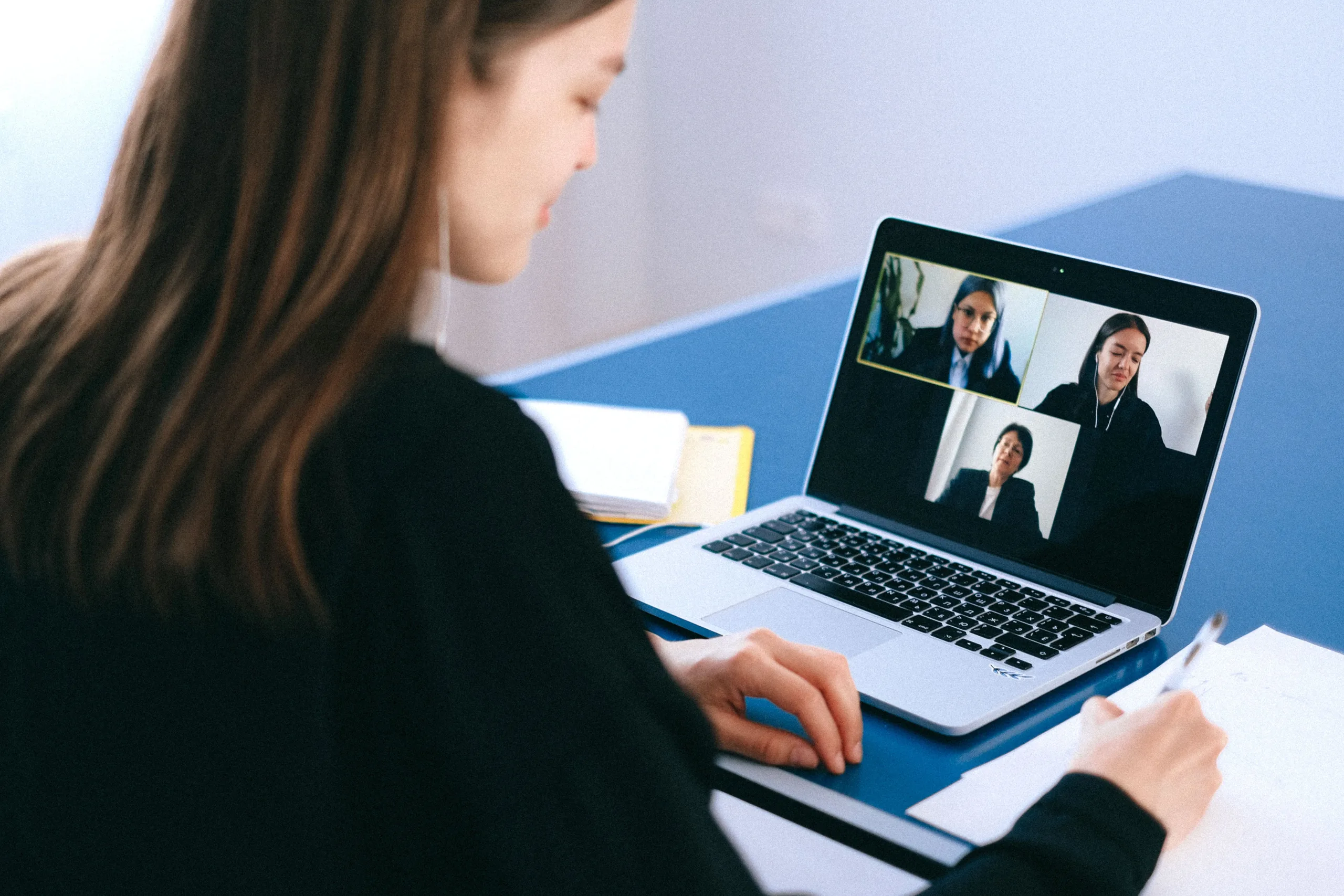 Practice manager on a video meeting from her laptop, taking notes