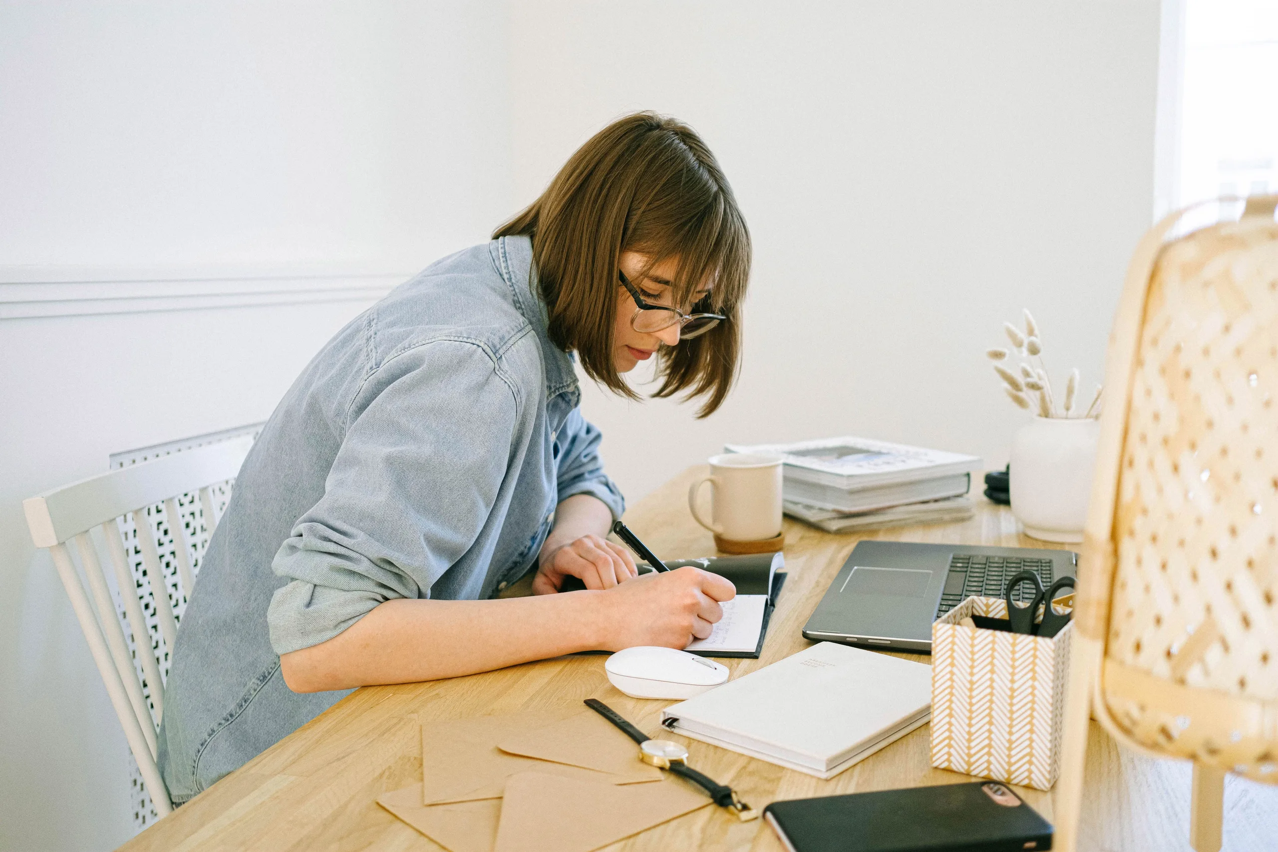 A sole practitioner at a home-office desk with a laptop and papers, working in natural daylight