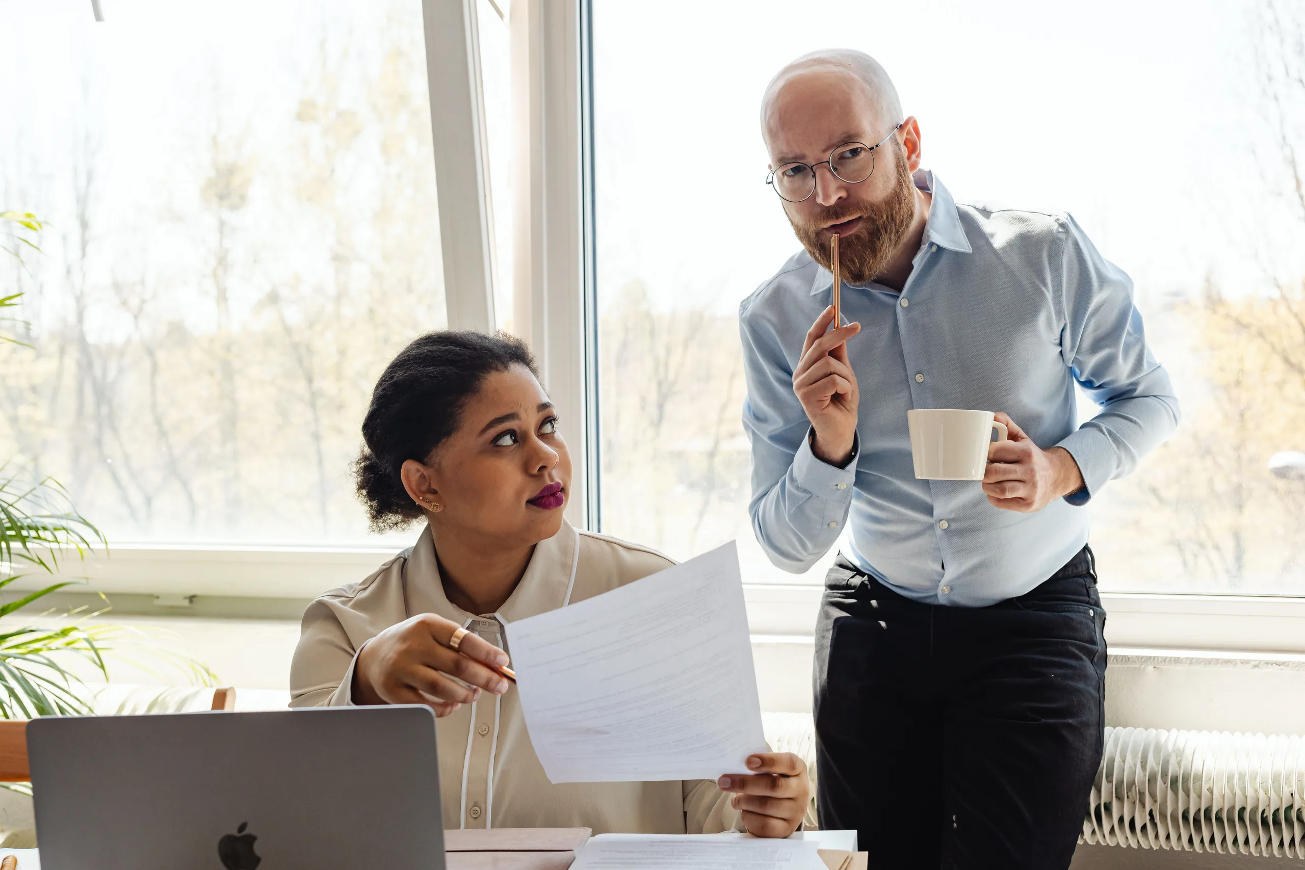 Two accountants reviewing a proposal together over a laptop and paperwork