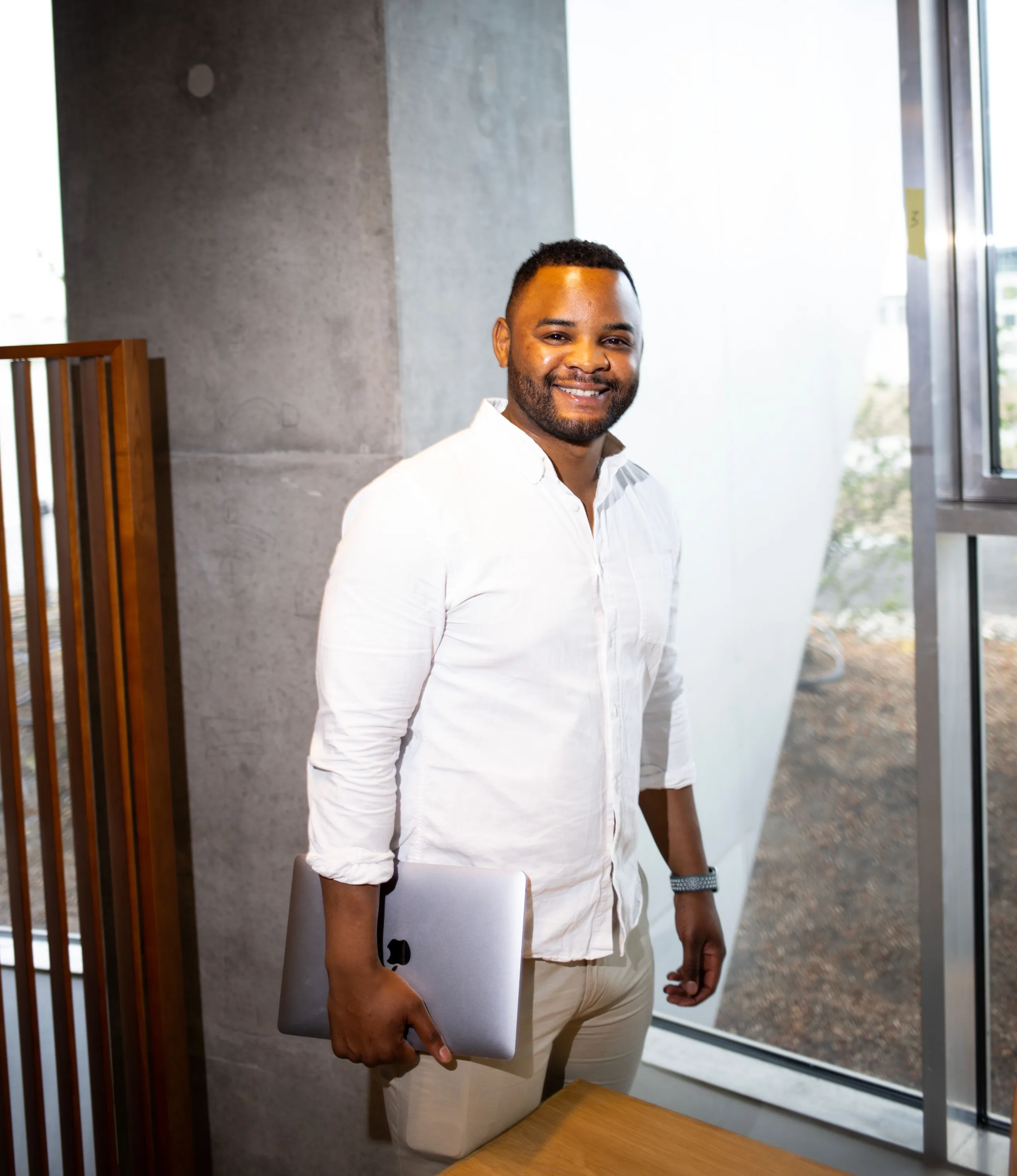 Smiling accountant holding a laptop by an office window
