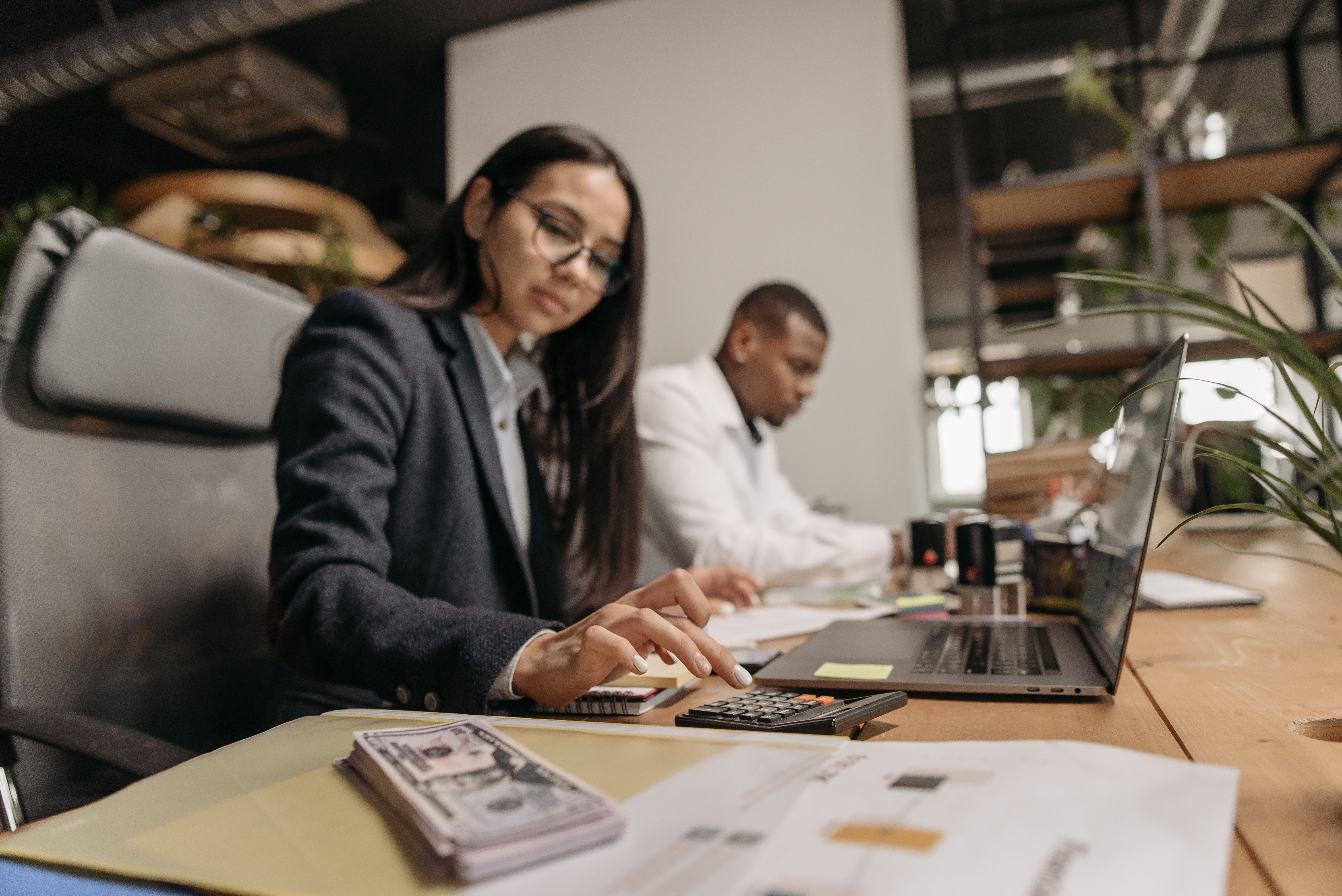 Two accountancy professionals reviewing figures together at a laptop and calculator