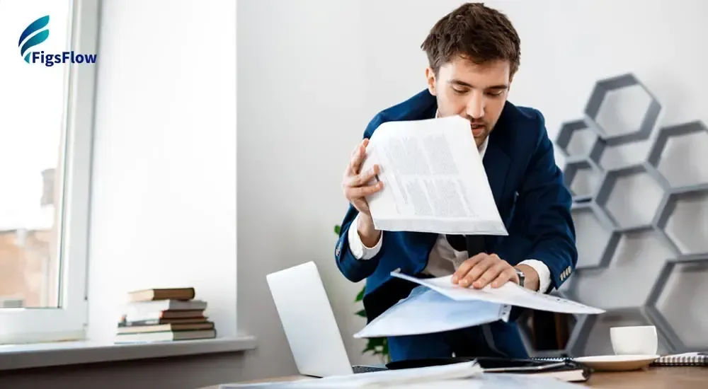 Stressed accountant in a suit sorting through stacks of paper documents at his desk, illustrating the burden of manual, paper-based practice management processes